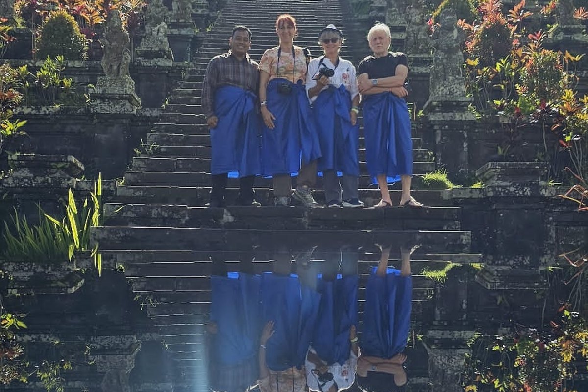 Tamu menuruni tangga pura dengan pantulan kolam di Bali