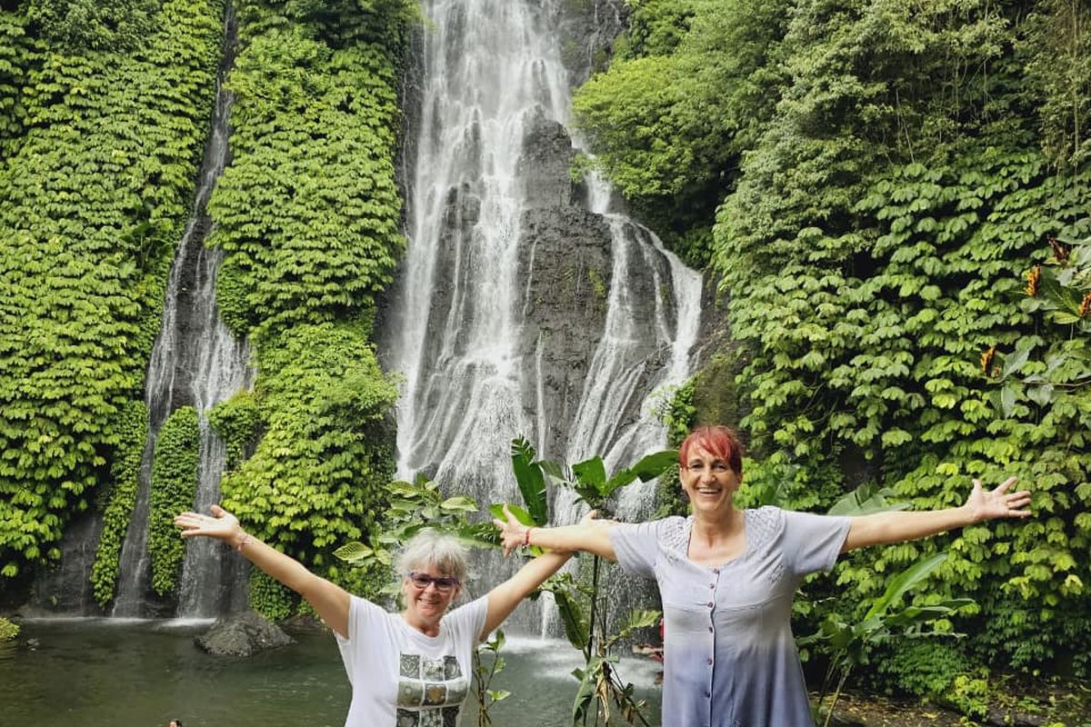 Dua tamu berfoto di depan air terjun saat tur Jawa Bali