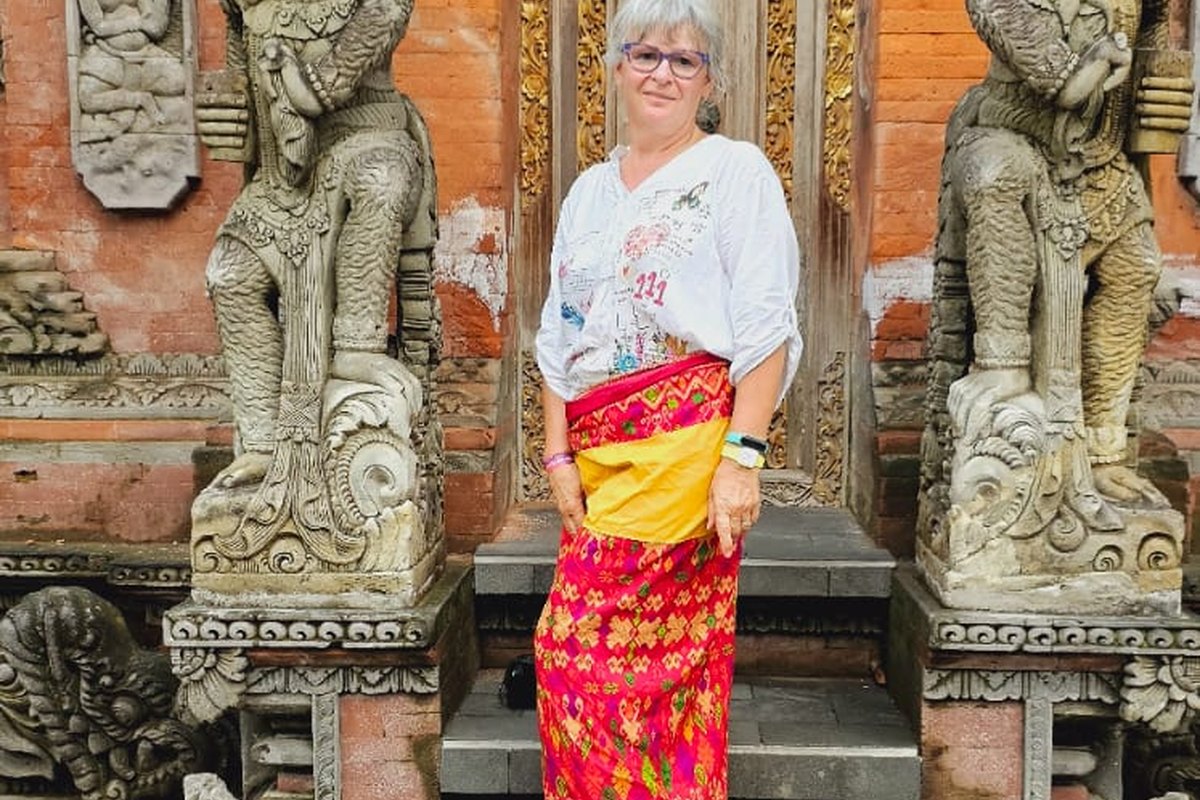 Tamu mengenakan kain tradisional di depan gapura pura Bali